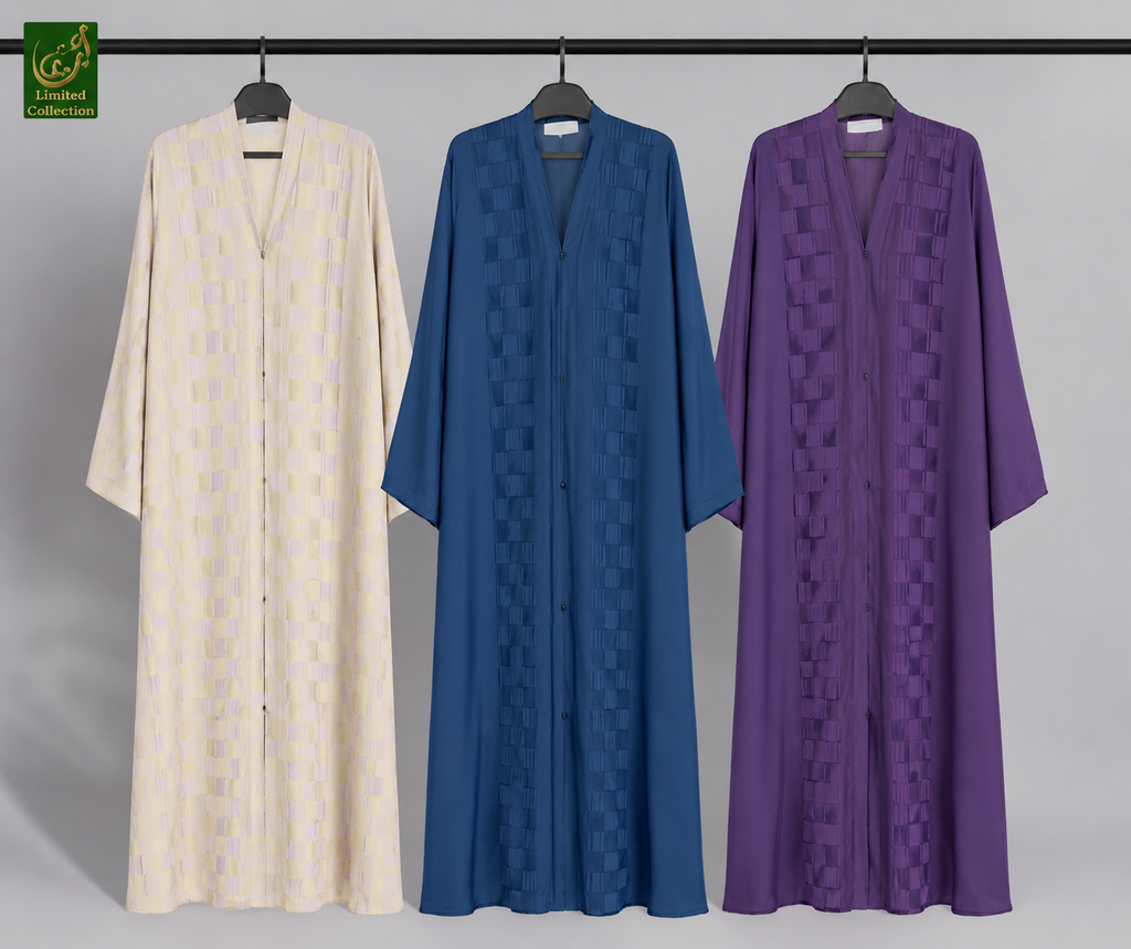 Three long open-front Abayas with side pockets hanging on black hangers against a light gray studio background. From left to right, the robes are cream with a subtle tonal pattern, medium blue with a tonal geometric pattern, and purple with a tonal geometric pattern.