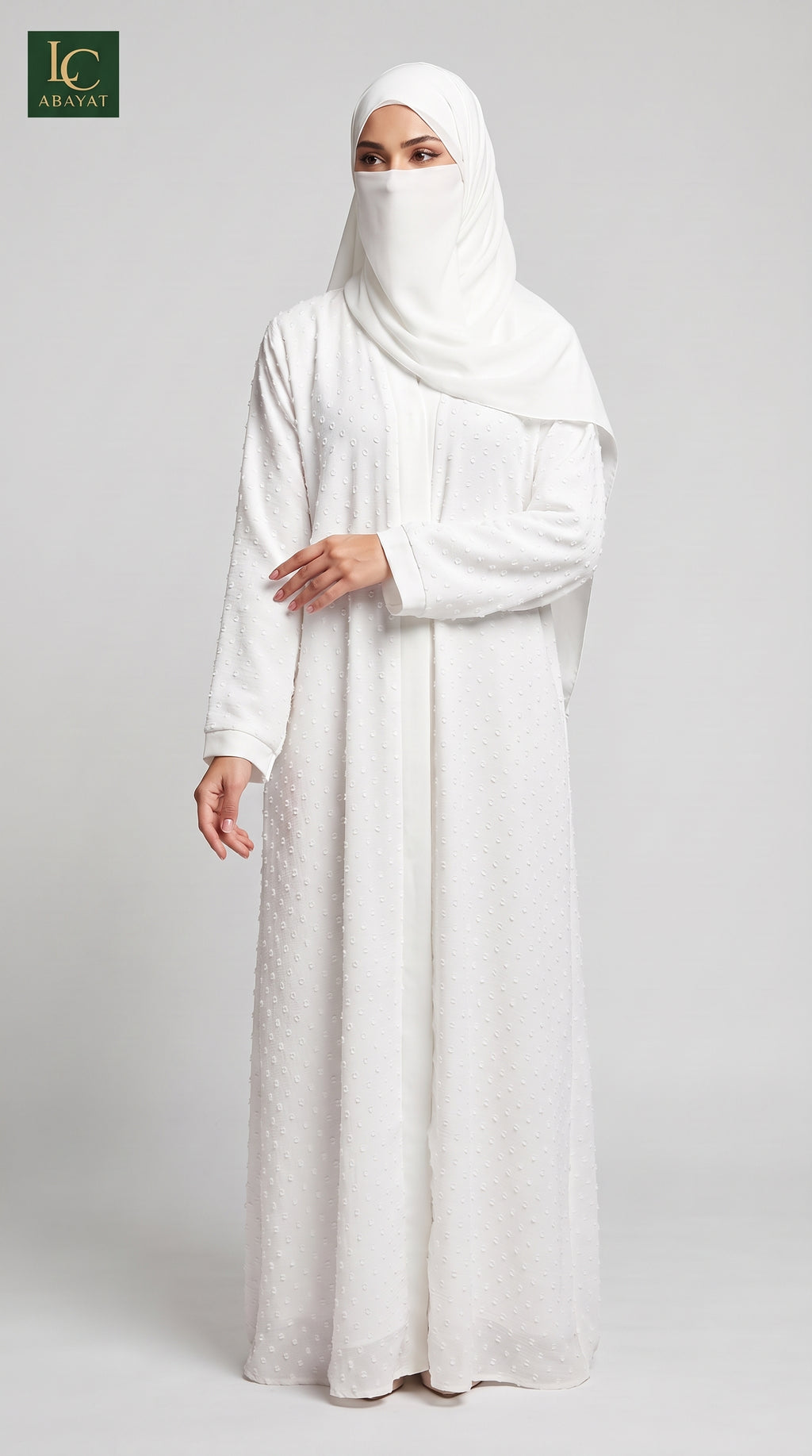 A woman wearing a long white abaya dress with a matching white hijab and face veil, standing against a light gray studio background. The logo for 'Al-Arayat' is visible in the top left corner.