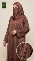 A woman wearing a brown Nida abaya with embroidered details and a matching brown hijab, shown against a plain beige background. A circular inset highlights the embroidery on the sleeve, and a 'Limited Collection' logo is visible in the top left corner.