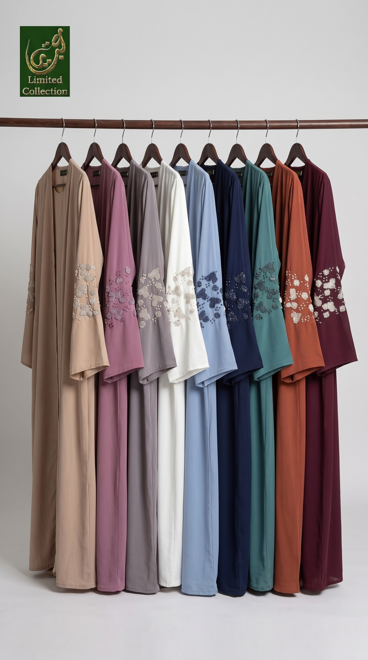 A row of loose, long-sleeve 3d CutdanA Abaya with attcahed inner in multiple colors hanging on a wooden rack against a light gray studio background. Each robe has floral embroidery near the lower front.