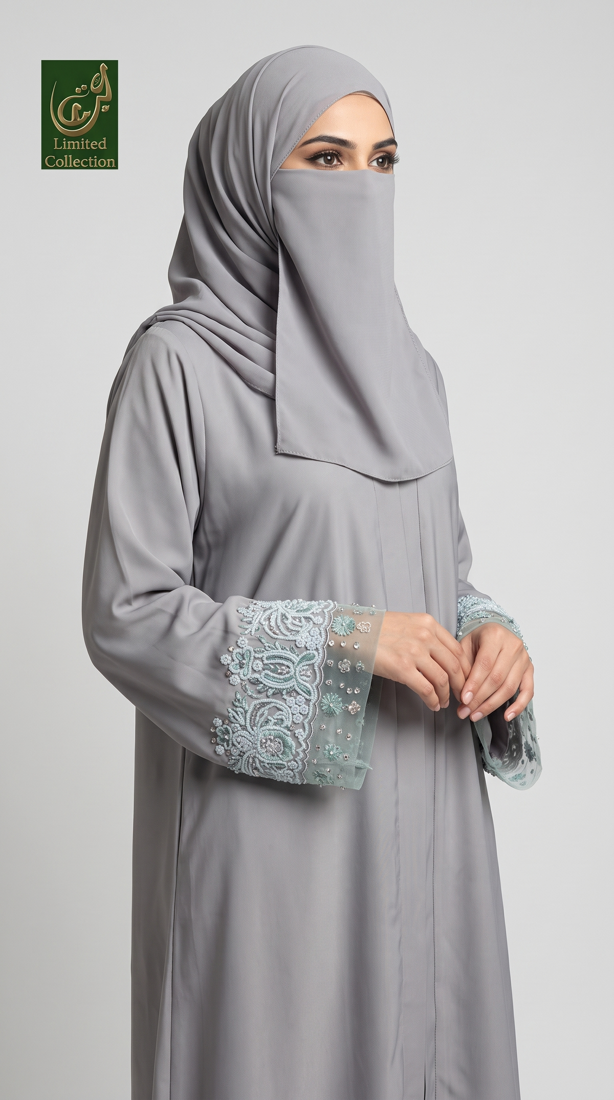 A woman wearing a light gray modest cutdana abaya with a matching hijab and a face veil, featuring light blue embroidered lace cuffs, posed against a neutral gray background. A 'Limited Collection' logo is visible in the top-left corner.