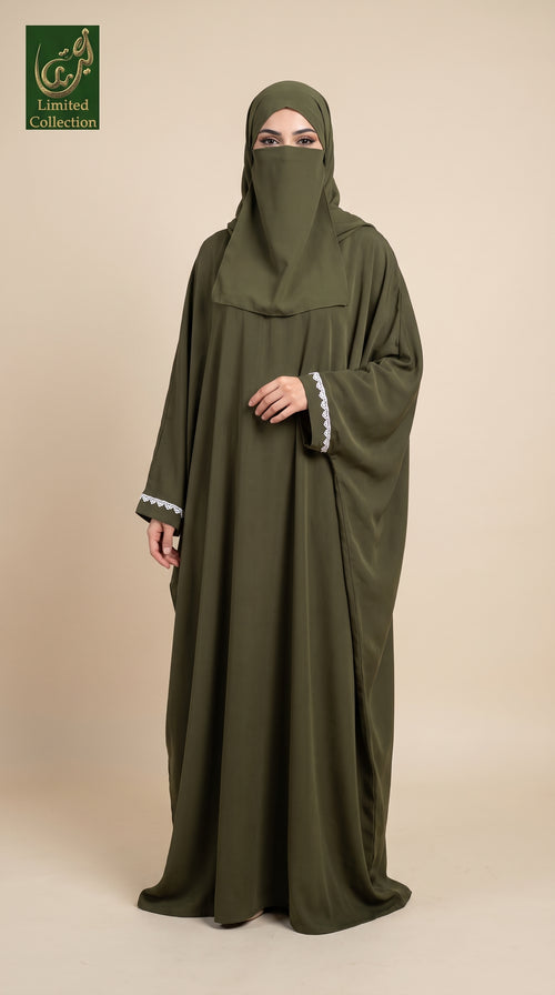 A woman wearing a long olive green abaya with a matching hijab and white lace trim on the cuffs, standing against a solid beige background. A logo for 'Limited Collection' is visible in the top-left corner.