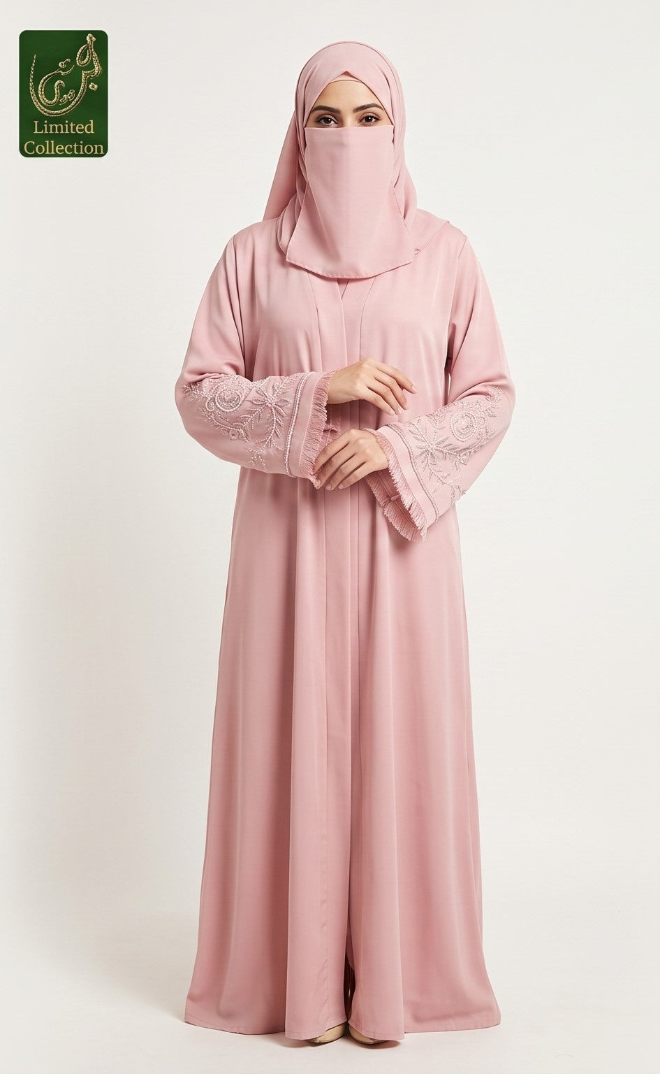 A woman wearing a light pink abaya with embroidered long sleeves and a matching pink hijab, standing against a plain light background. A green 'Limited Collection' logo is visible in the top-left corner.