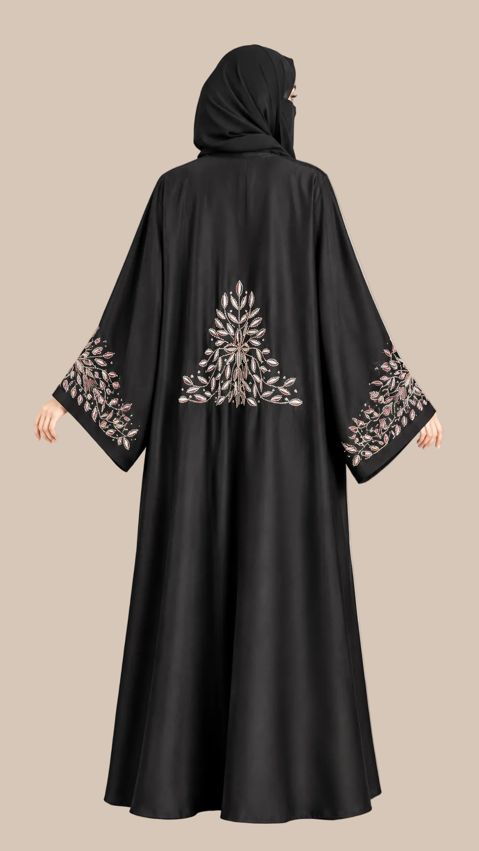 A woman wearing a black abaya with intricate silver and white floral embroidery on the back and wide sleeves, paired with a matching black hijab. The photo is taken from the back against a solid beige studio background.